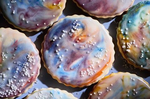 Close up of Northern Lights Iced Sugar Cookies tightly arranged on a blue background - select to zoom