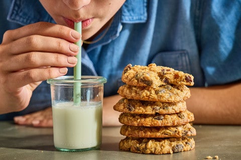 Drinking from a glass of milk that is sitting next to a stack of The Softest Oatmeal Raisin Cookies - select to zoom