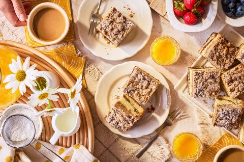 A table arranged with slices of Our Favorite Sour Cream Coffee Cake and other breakfast items. - select to zoom