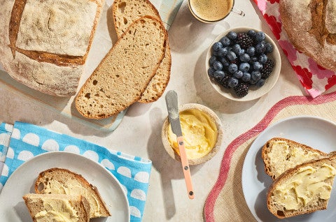 Naturally Leavened Sourdough Bread sliced and shown on a decorated table with butter and blueberries - select to zoom