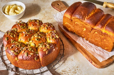 Pumpkin Milk Bread on a counter baked as rolls and a loaf of bread - select to zoom