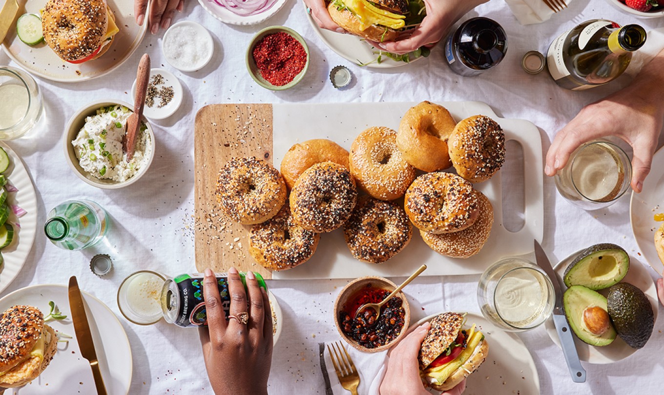 A tablescape set with Ultimate Sandwich Bagels and friends gather around