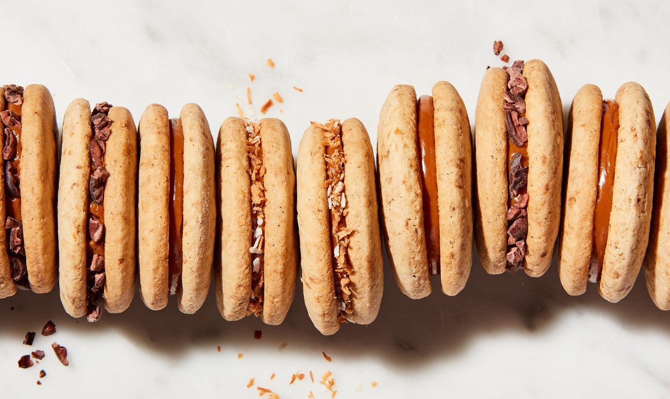 Cola de Mono Alfajores (dulce de leche sandwich cookies) lined up, coated in different garnishes