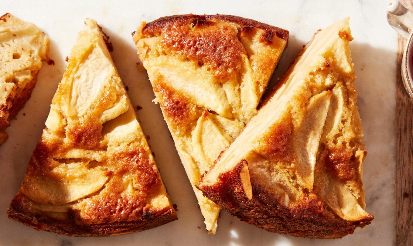 Slices of Mostly Apples Apple Cake next to each other on a platter with tea
