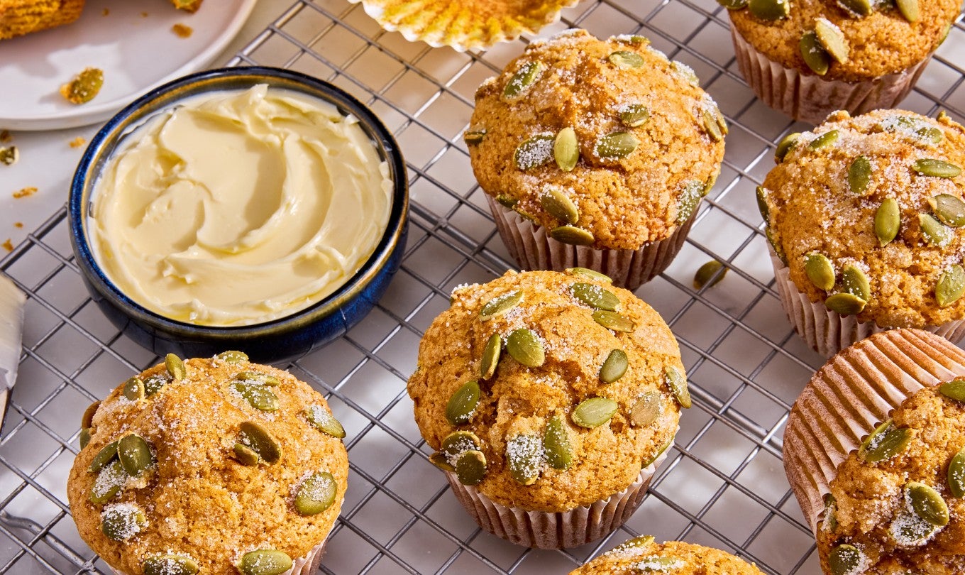 Easy Pumpkin Muffins on a cooling rack with a dish of butter