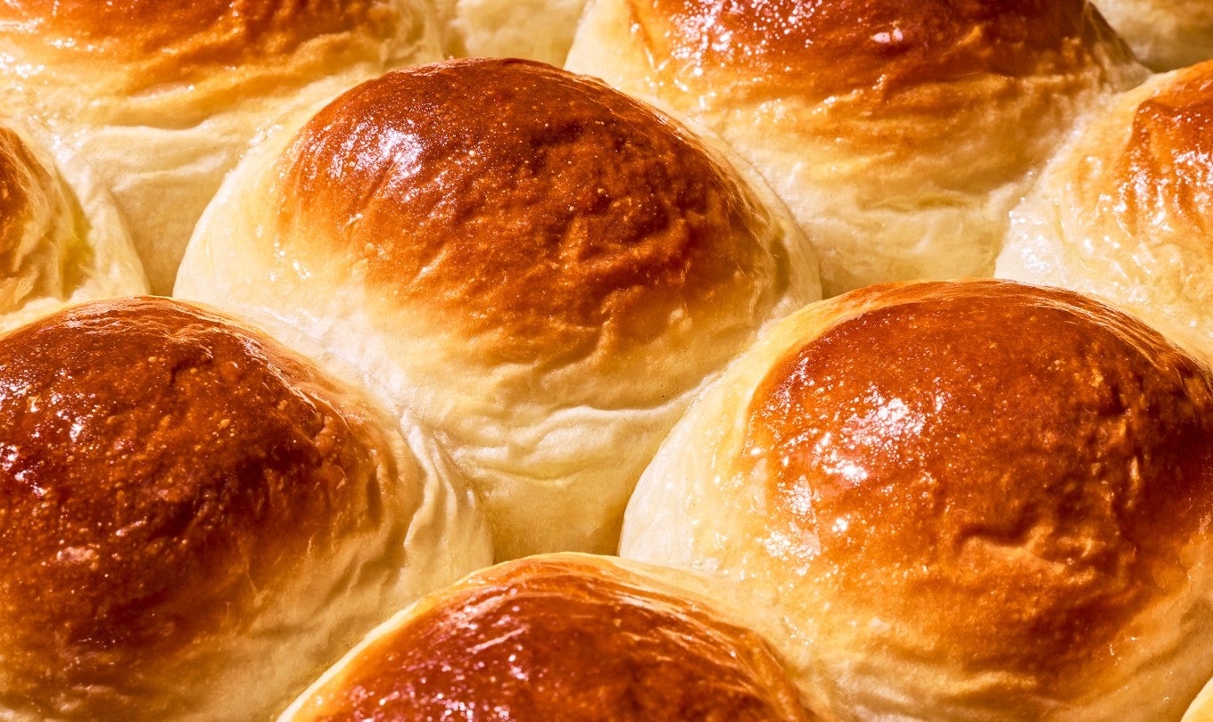 Side view of perfectly browned rolls fresh out of the oven and grouped together.