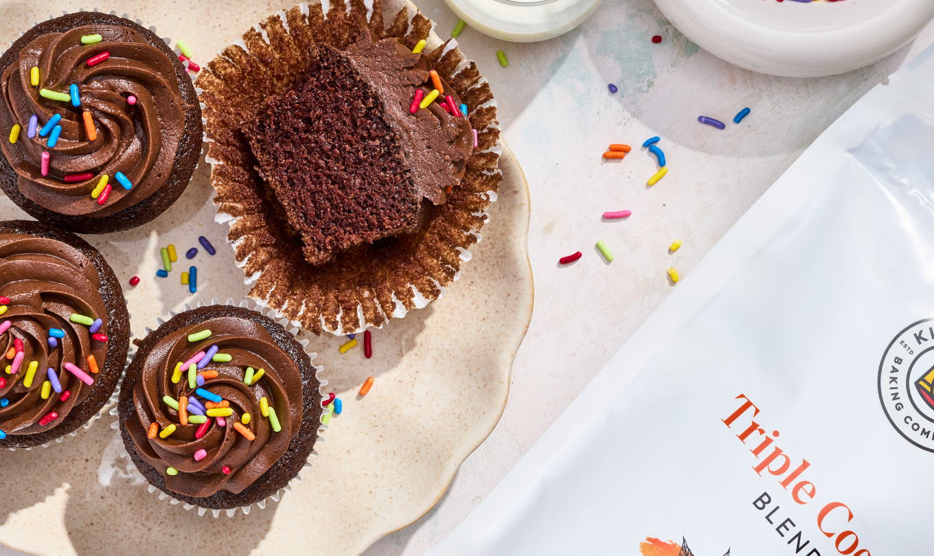 Small-Batch Chocolate Cupcakes on a plate with a bag of King Arthur Baking's triple cocoa powder in the corner of the frame.