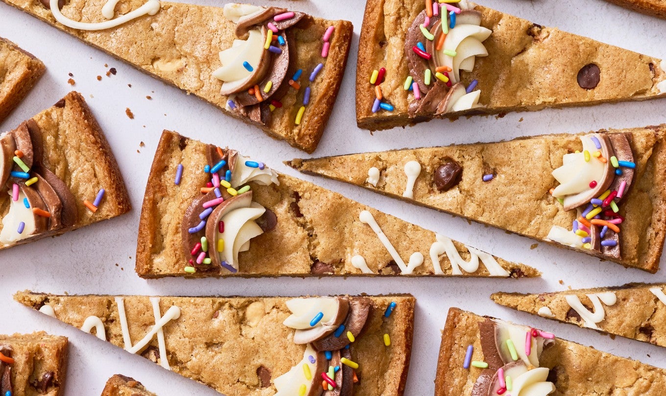 Slices of chocolate chip cookie cake arranged on a table top.