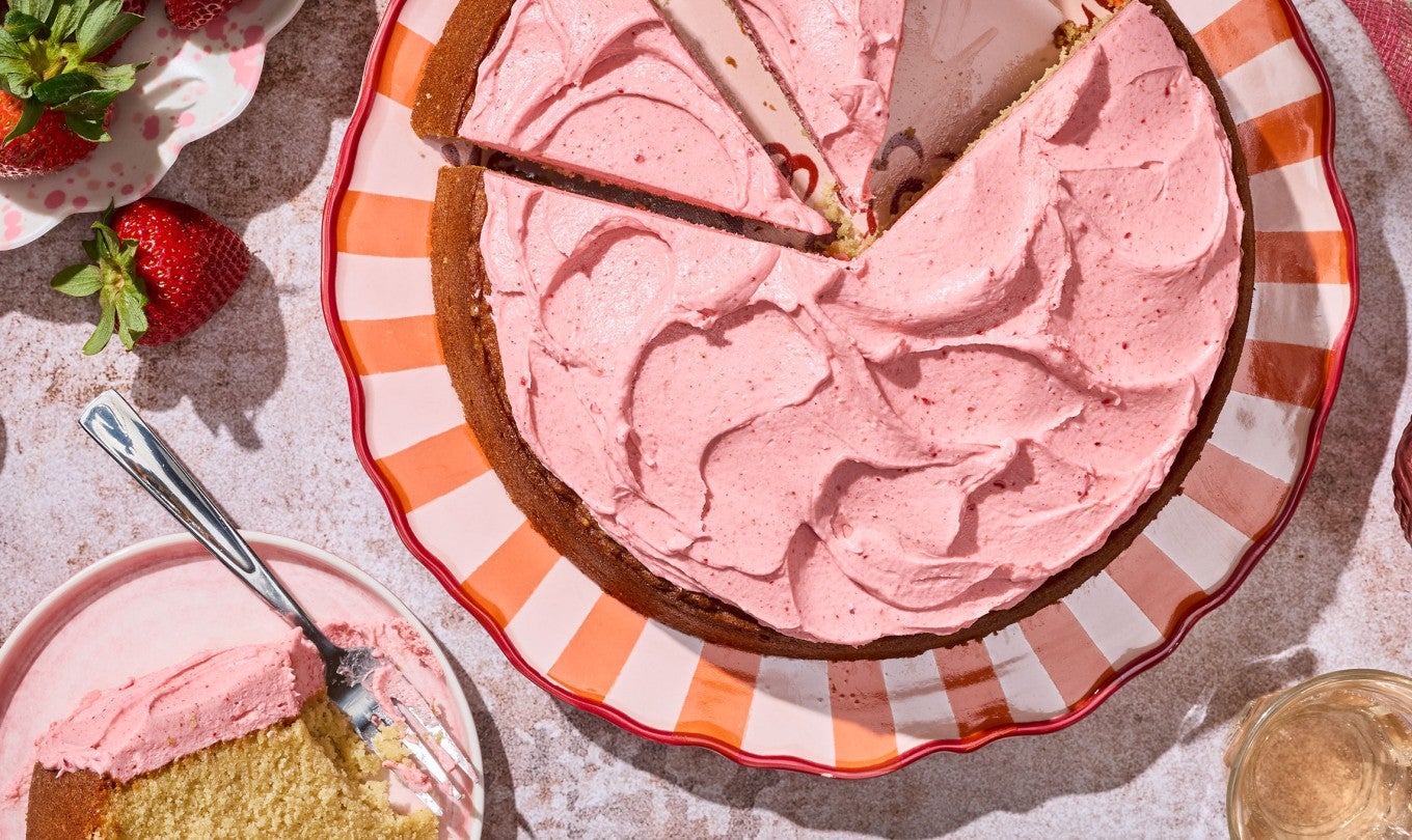 Brown Sugar Strawberry Frosted Cake on a table on a striped plate.