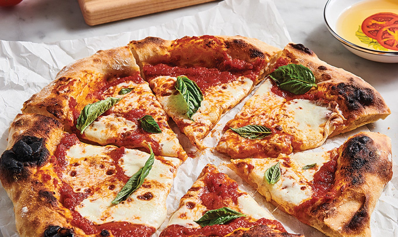 A Neapolitan pizza sliced on a piece of parchement.