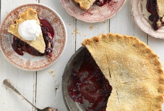 A cherry pie made with a gluten-free crust with a few slices on plates, ready to be enjoyed