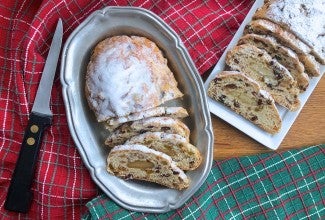 Two loaves of Christmas Stollen, sliced on plates on a table.