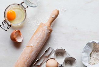 Eggs, a rolling pin, and a bag of flour on a kitchen counter