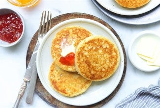 Three buttered sourdough crumpets on a plate.