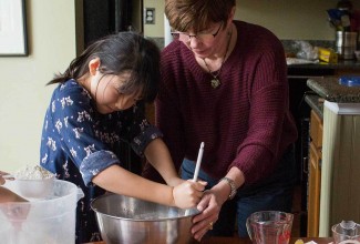 A mother and a daughter baking together happily