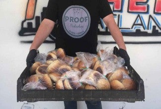 Baker holding bags of baked goods