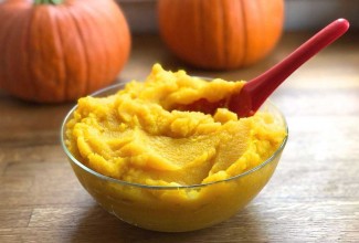 Bowl of pumpkin purée with pumpkins in background