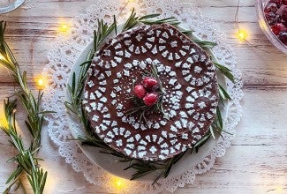 A flourless chocolate cake stenciled with confectioners' sugar, cranberries, and twinkling lights