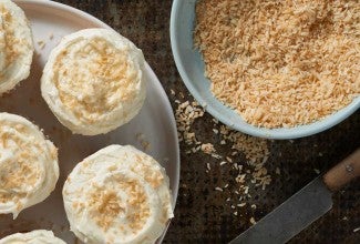 Bowl of toasted coconut next to cupcakes