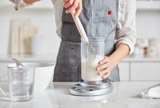 Baker mixing starter with dough whisk