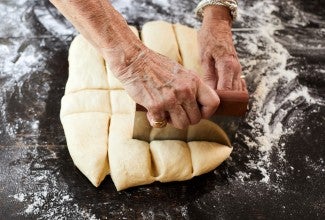 Hands cutting dough into rolls