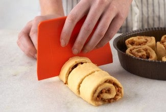 Using dough scraper to cut rolls 