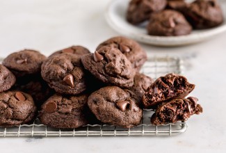 A pile of double chocolate chip cookies on a cooling rack.