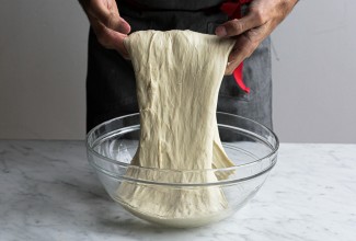 Baker using hands to fold breading dough