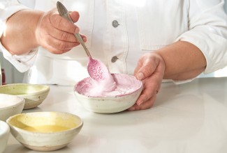 Hands mixing frosting with natural pink coloring