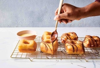 Hand adding chocolate glaze to doughnuts