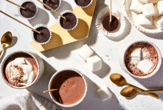 Mugs of keto hot chocolate alongside various toppings