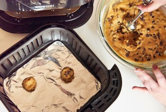 Scooping chocolate chip cookies dough into air fryer basket 