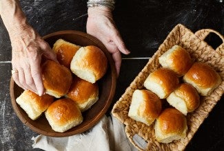 Elder woman's hand serving dinner rolls