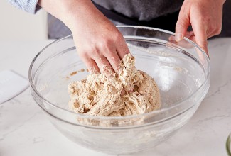 Hands covered in sticky bread dough while kneading