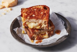 French onion grilled cheese sandwich cut in quarters, two pieces stacked on a plate