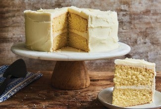 Slice of Golden Vanilla Cake, with full cake in background