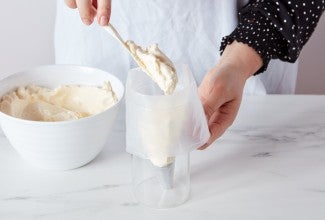 Baker fill pastry bag set in a drinking glass