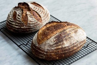 Two loaves of baked bread on cooling rack