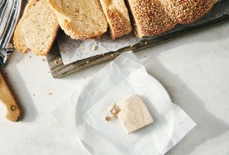 Block of fresh yeast in front of loaf of sliced bread