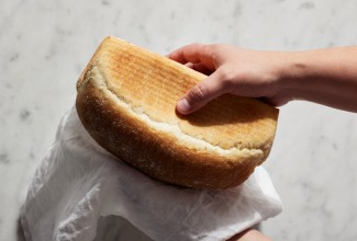 Baker squeezing a loaf of baked sandwich bread
