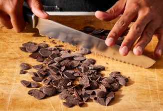 Baker chopping chocolate with serrated knife