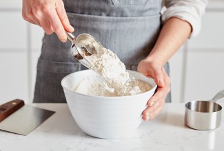 Baker scooping white flour into measuring cup