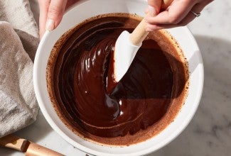 Baker using spatula to stir a bowl of ganache