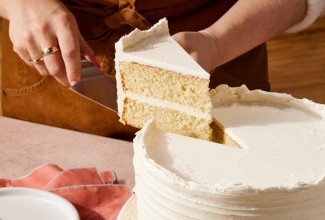 Baker cutting a slice of white velvet cake