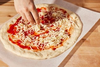 Topping unbaked pizza with shredded cheese