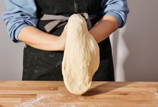 Baker stretching pizza dough into a circle