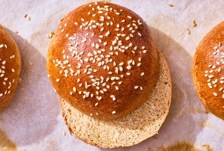 100% Whole Wheat Hamburger Buns sliced and on parchment paper