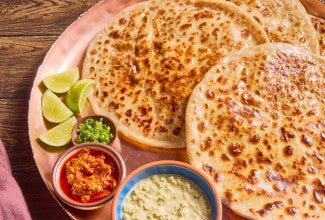 Aloo Paratha (Spiced Potato-Stuffed Flatbread) on a serving plate with lime