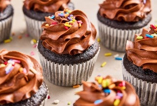 A bunch of Bake Sale Fudge Cupcakes topped with rainbow sprinkles