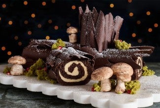Chocolate Buche de Noel with Cookie Butter Whipped Ganache seen from the side with edible woodland decorations.
